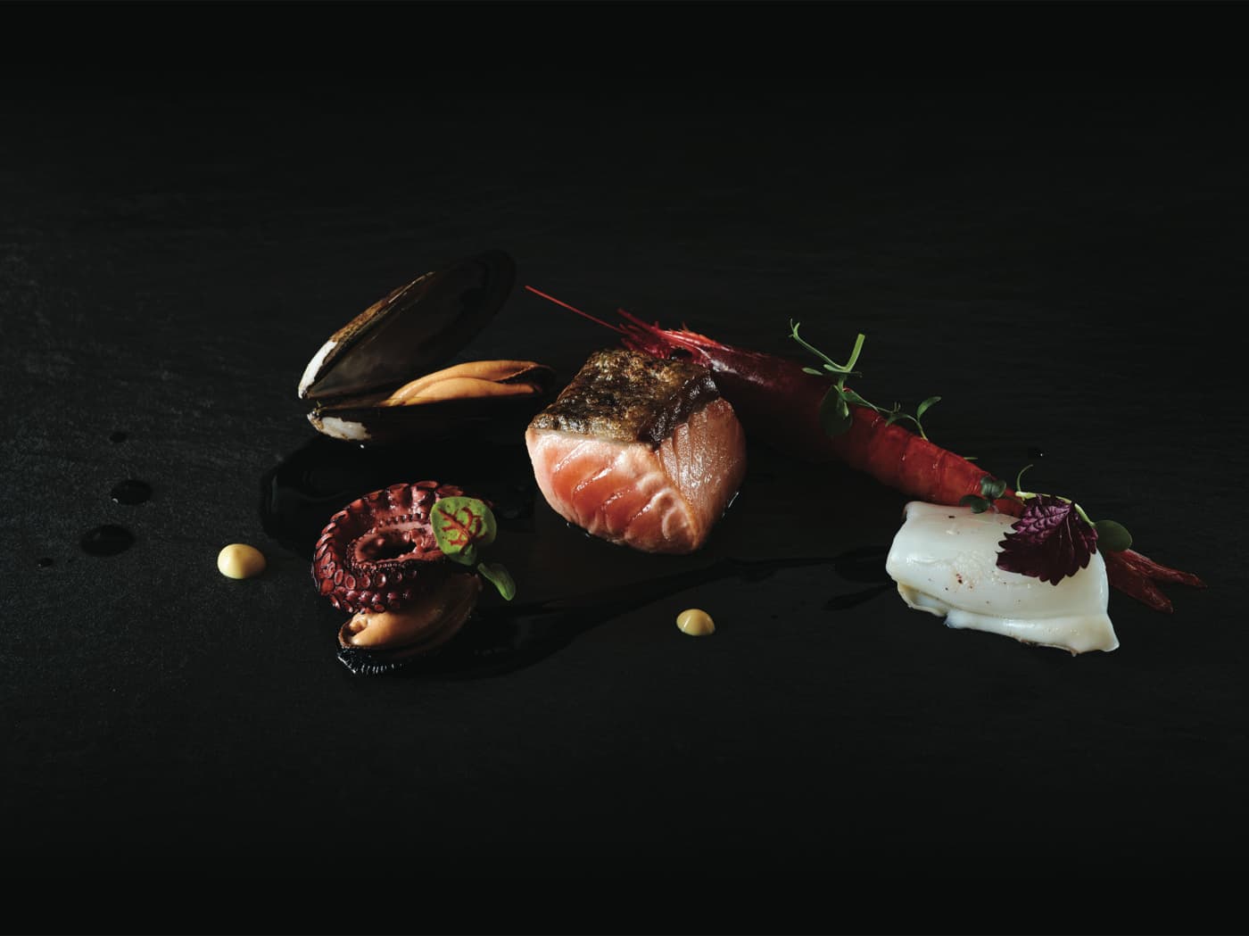 La quintessenza del mare: il salmone Upstream con cozze, gamberi, polpo e crema di nero di seppia